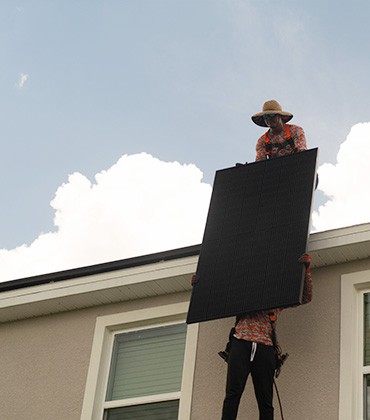 Solar installers lifting panels onto roof